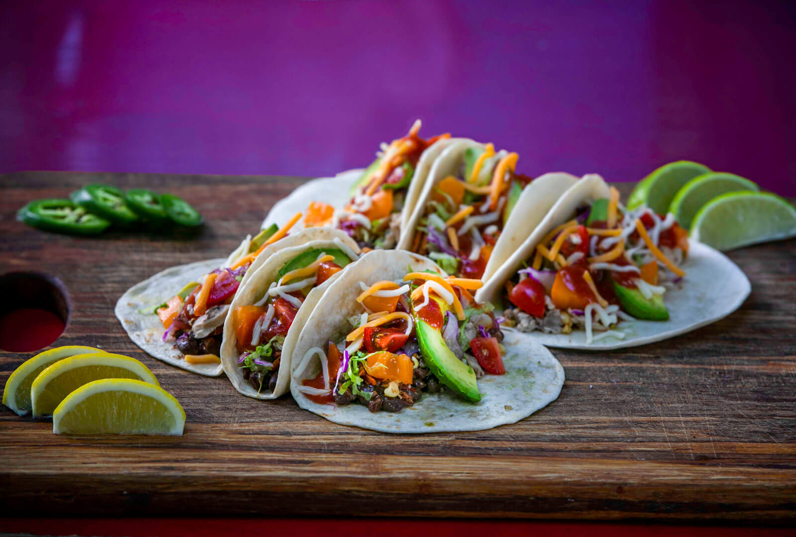 6 flavorful MegaMex tacos on a plate with a bright purple background