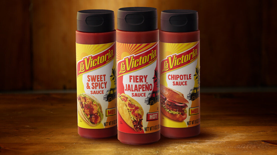 Three LA VICTORIA® topping sauces next to each other on a wooden countertop.