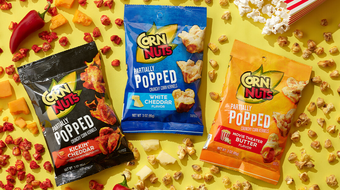 CORN NUTS® Partially Popped corn kernel flavors on a yellow background with partially popped corn kernels around each bag.