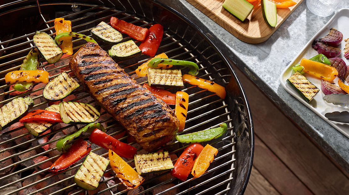 Pork Loin on a grill surrounded by various vegetables