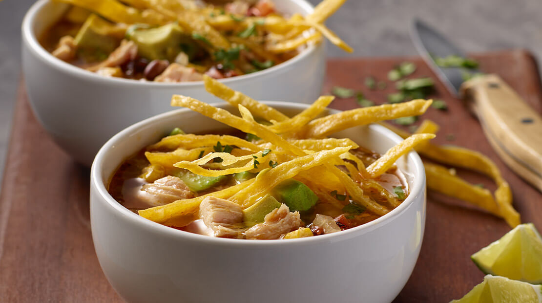 Chicken Tortilla Soup in a white bowl on a wooden surface