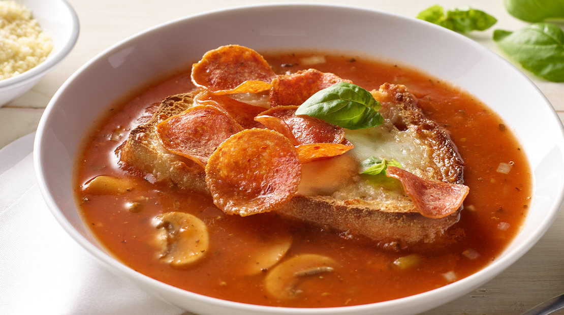 Pepperoni Pizza Soup in a white bowl on a white surface