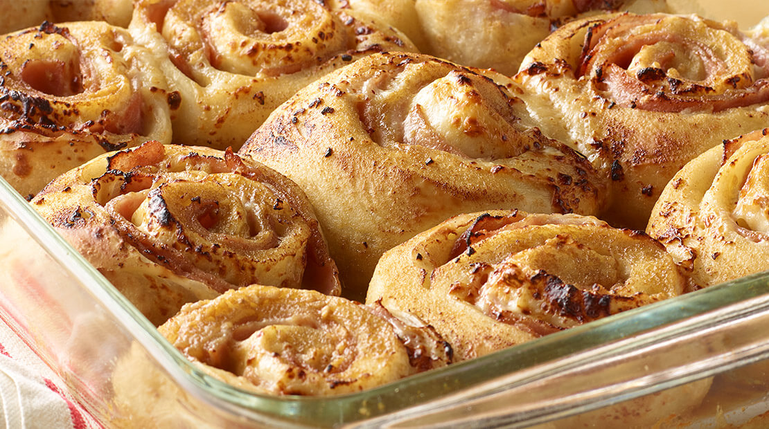 Ham and cheese rolls in a glass baking dish