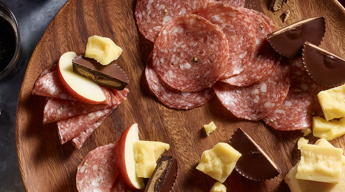 Italian Dry Salami, chocolate, peanuts and apple featured on a platter