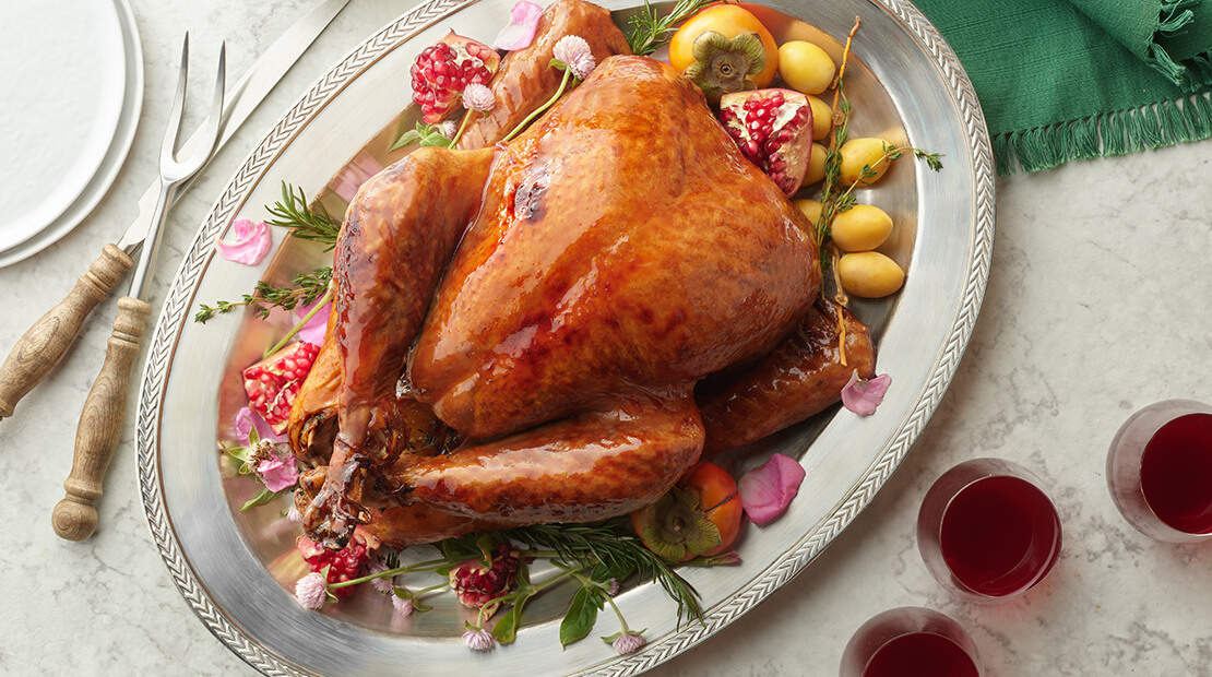 Persian whole turkey on a silver platter with roasted potatoes around the turkey.