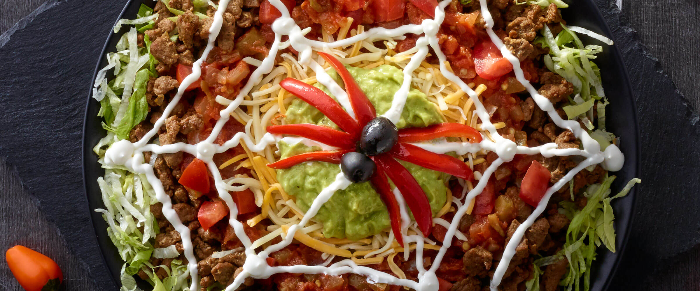 Spidery Nacho Dip on a platter surrounded by orange peppers and candy corn