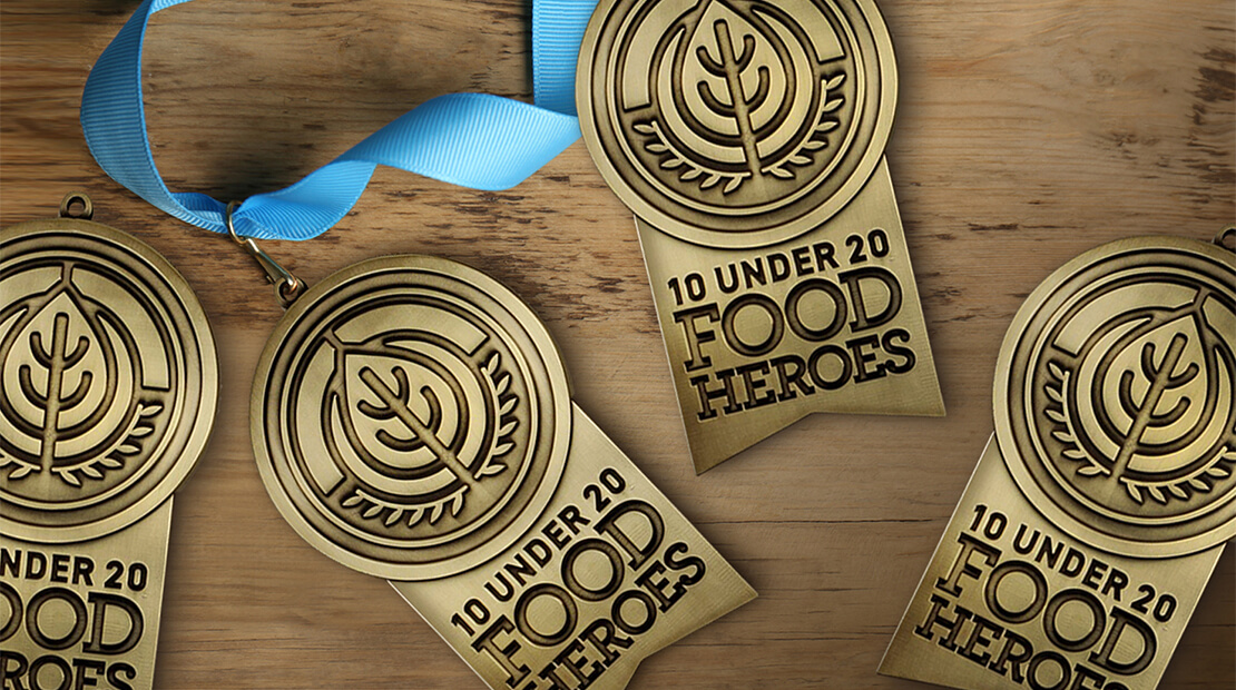 Four 10 Under 20 Medallions on a wooden table.