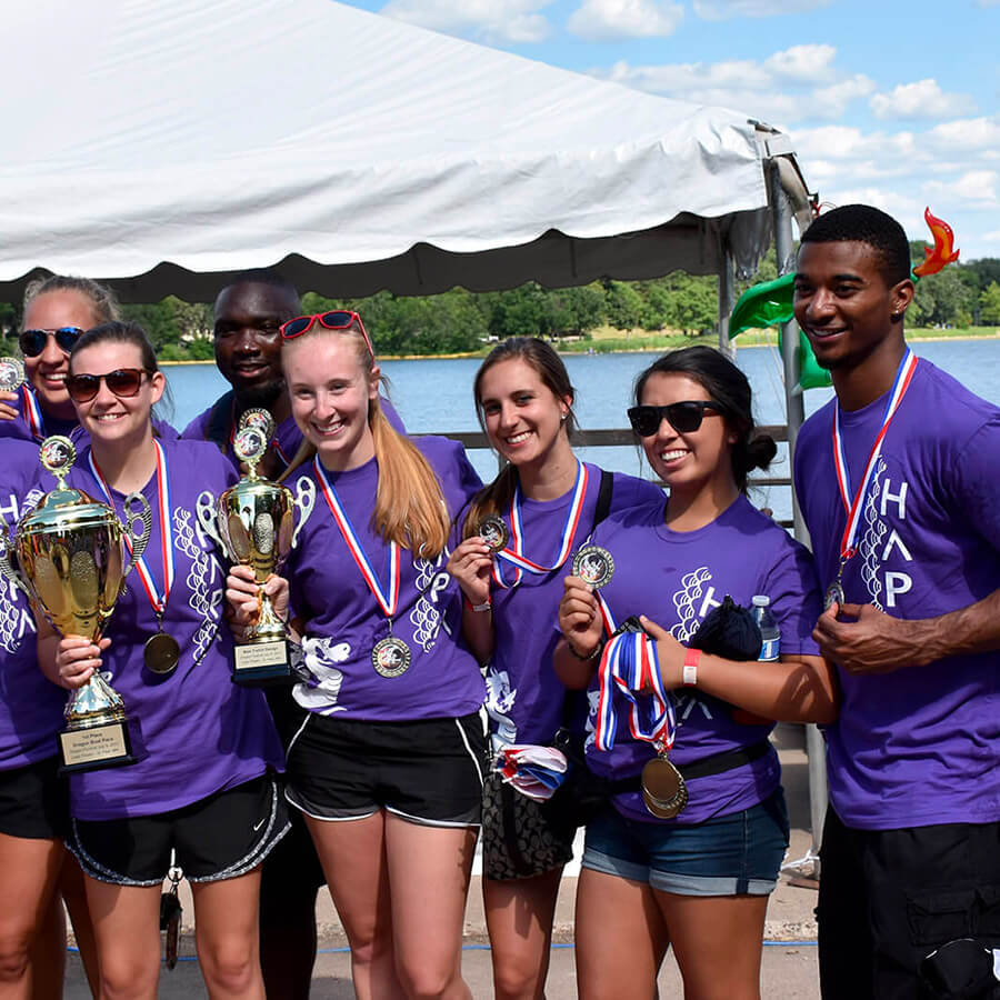 a team of young people wearing purple shirts hold trophies and medals