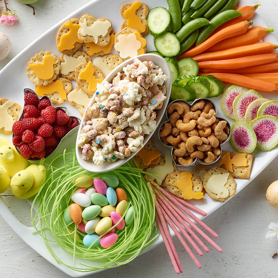 Spring charcuterie board with crackers, veggies, candy eggs & fruit