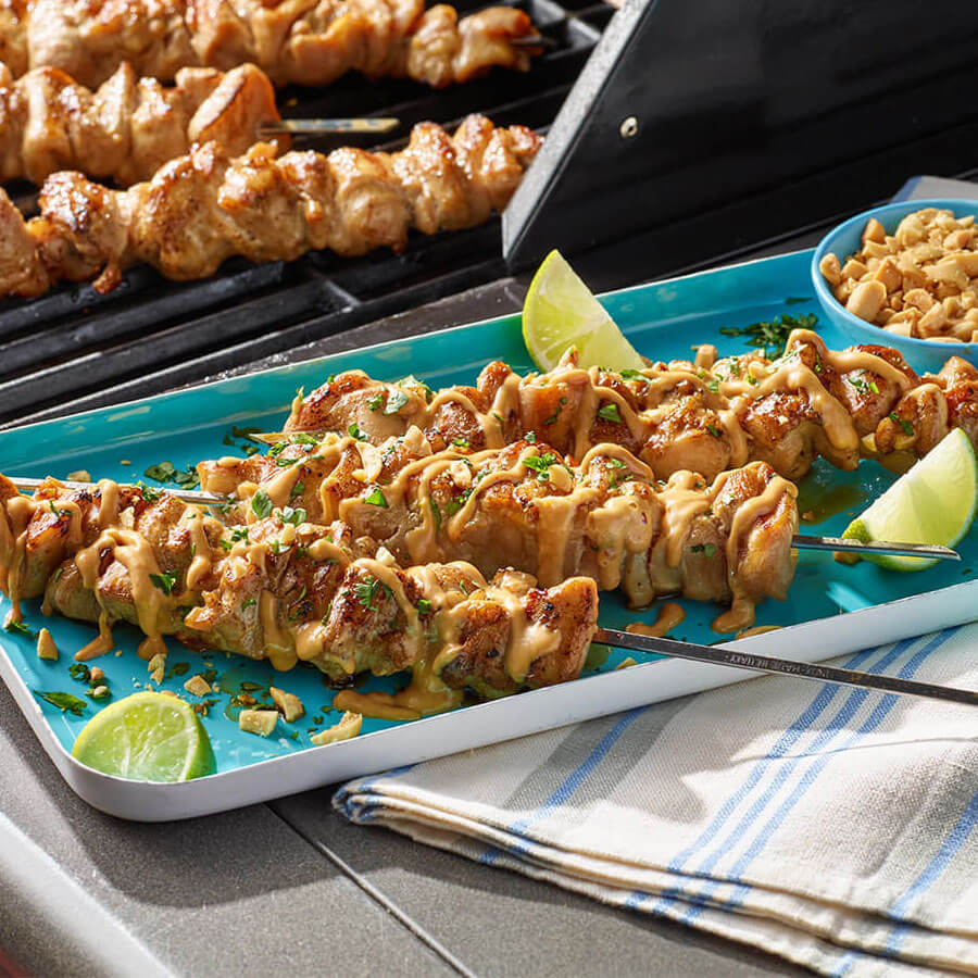 Thai chicken skewers on a blue platter with limes