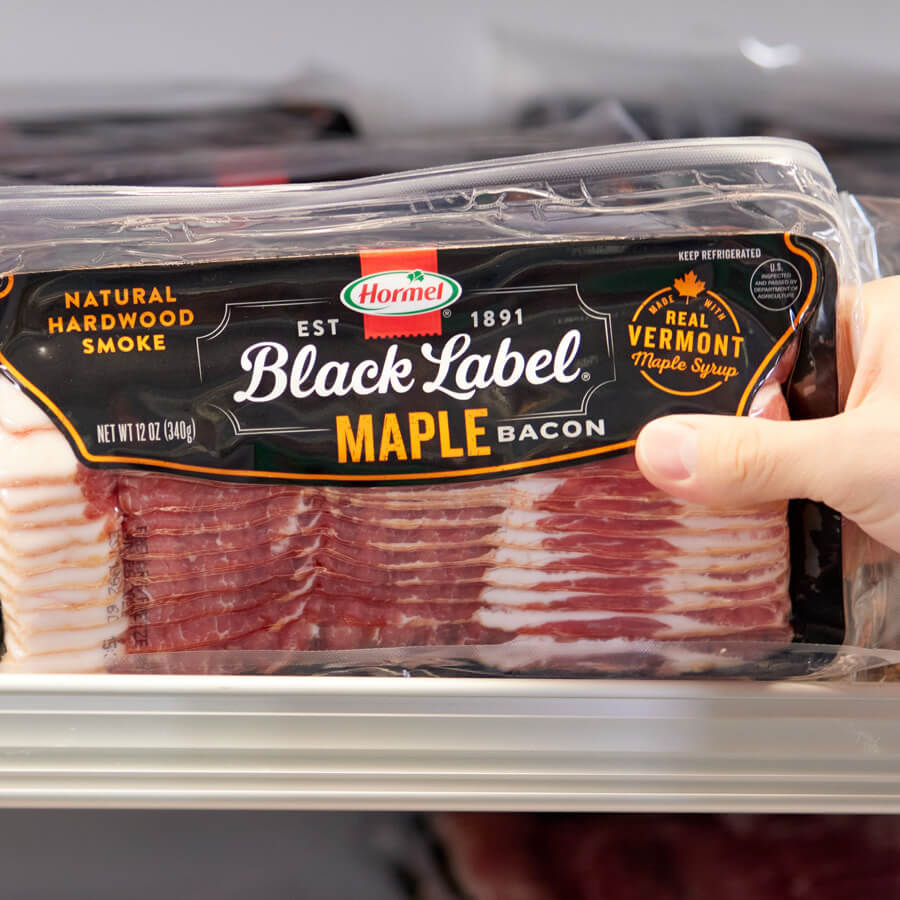 Hand reaching for Black Label Bacon on grocery store shelf