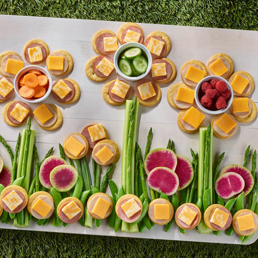 spring flowers cheese & cracker board on white tray with grass background