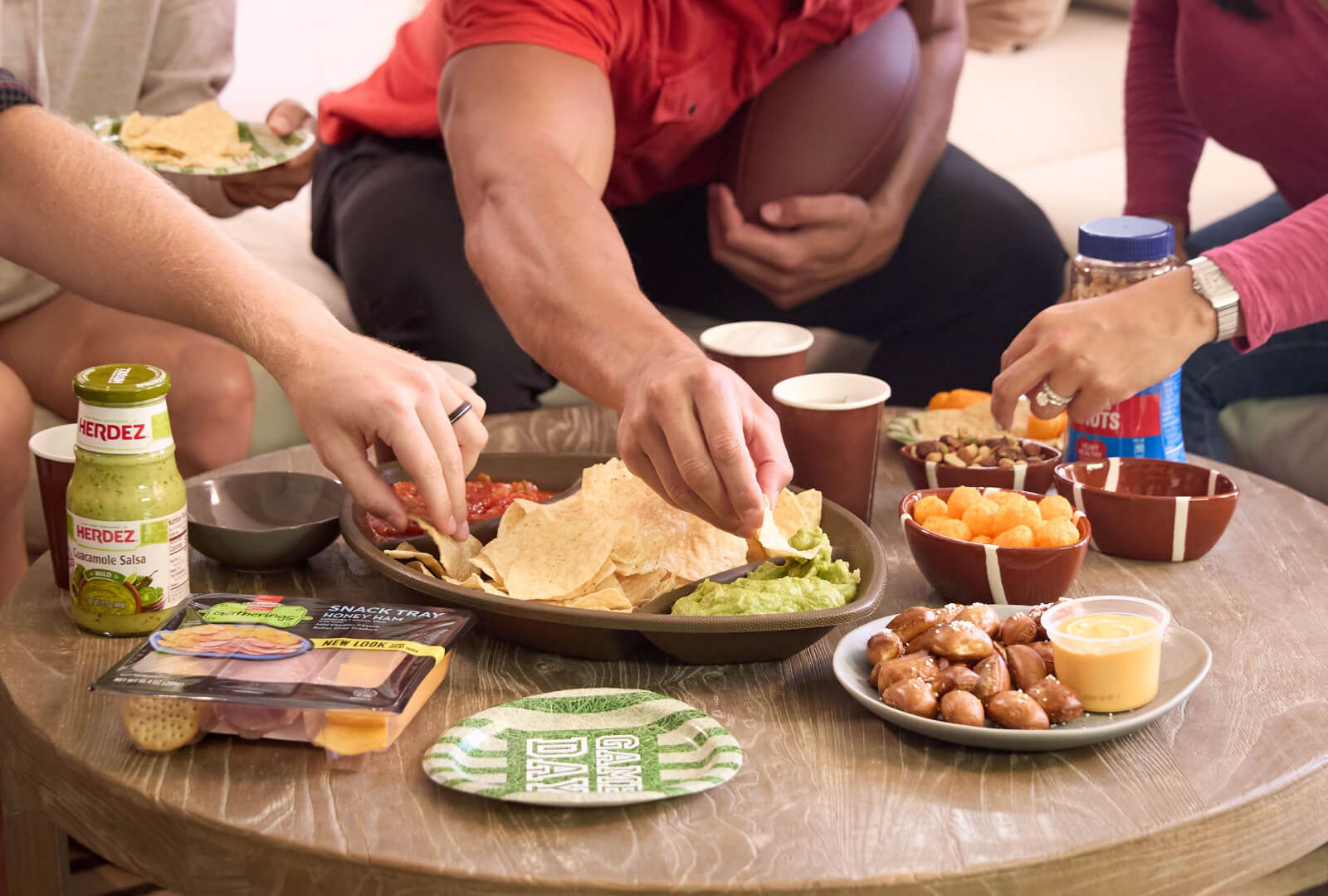 Plate full of game day food with fans reaching for a bite.