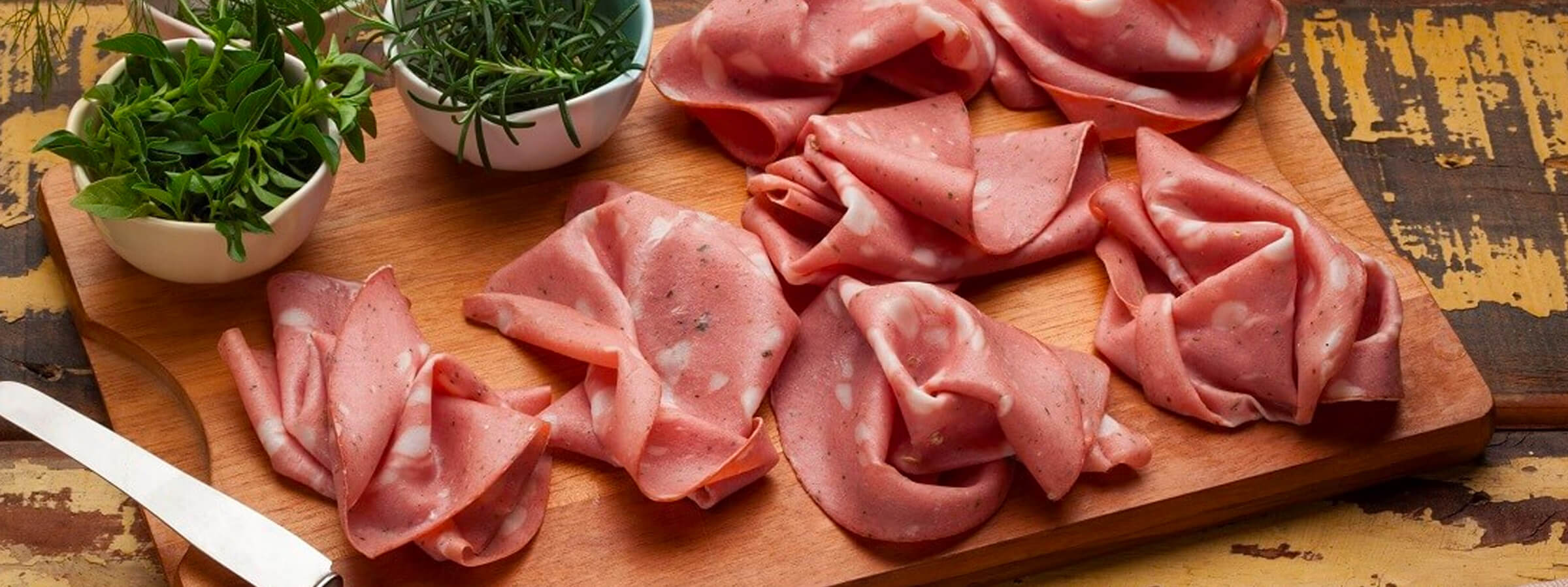 a serving board with meat slices and fresh herbs