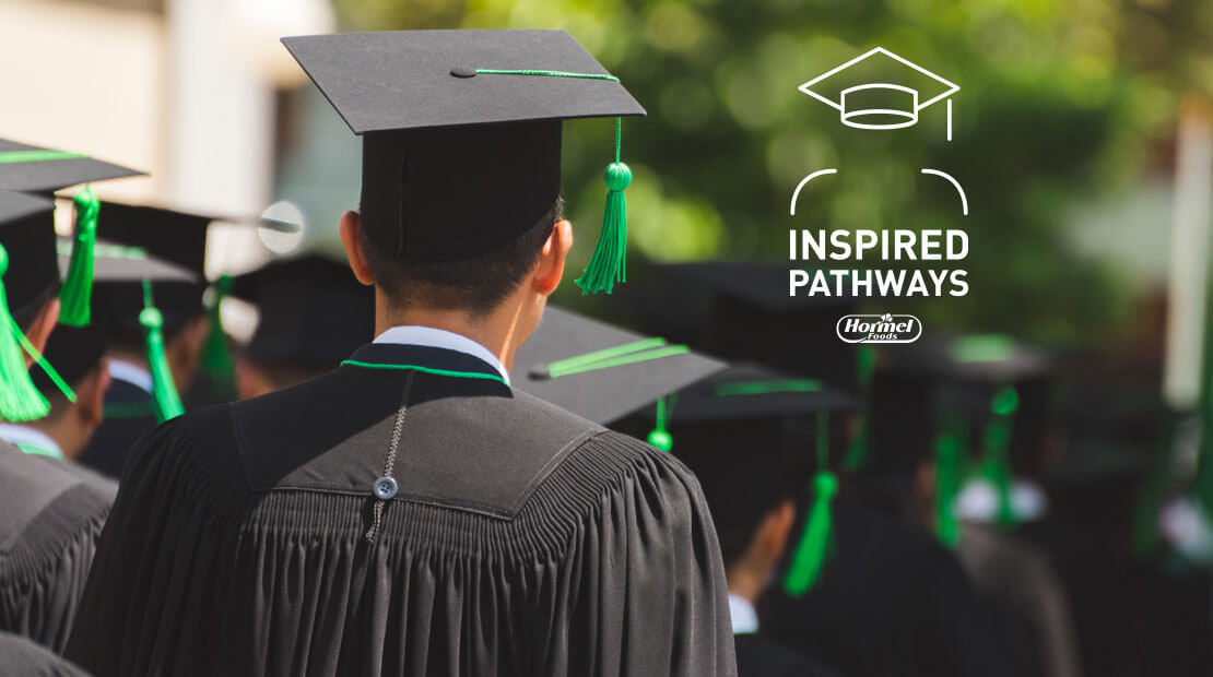 Inspired Pathways graduates walking outdoors with green tassels on mortarboard