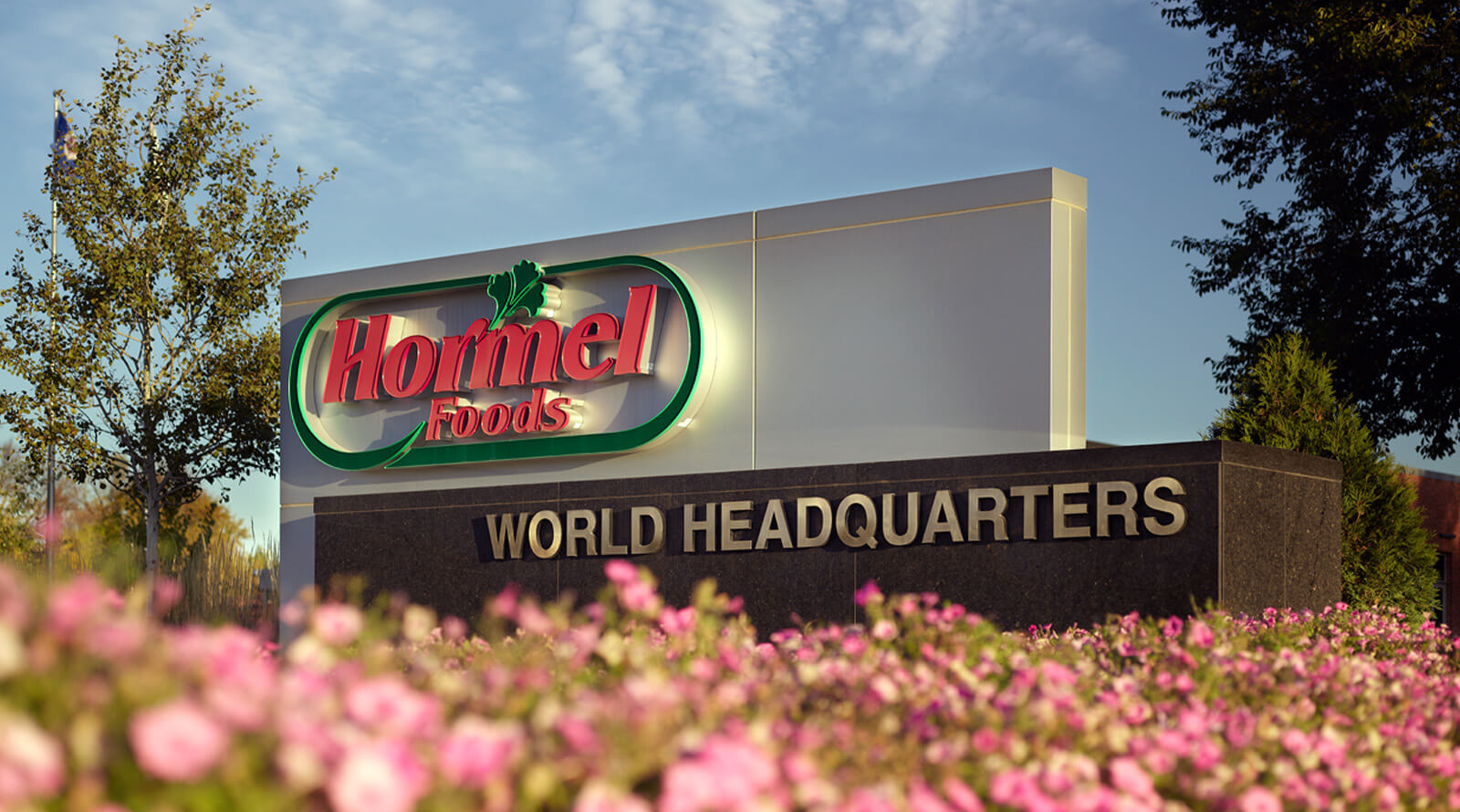 Hormel Foods headquarters sign with pink flowers in foreground