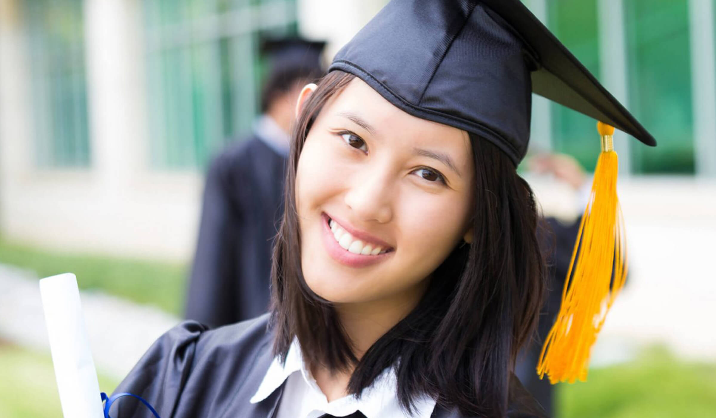 College graduate with cap & gown holding diploma