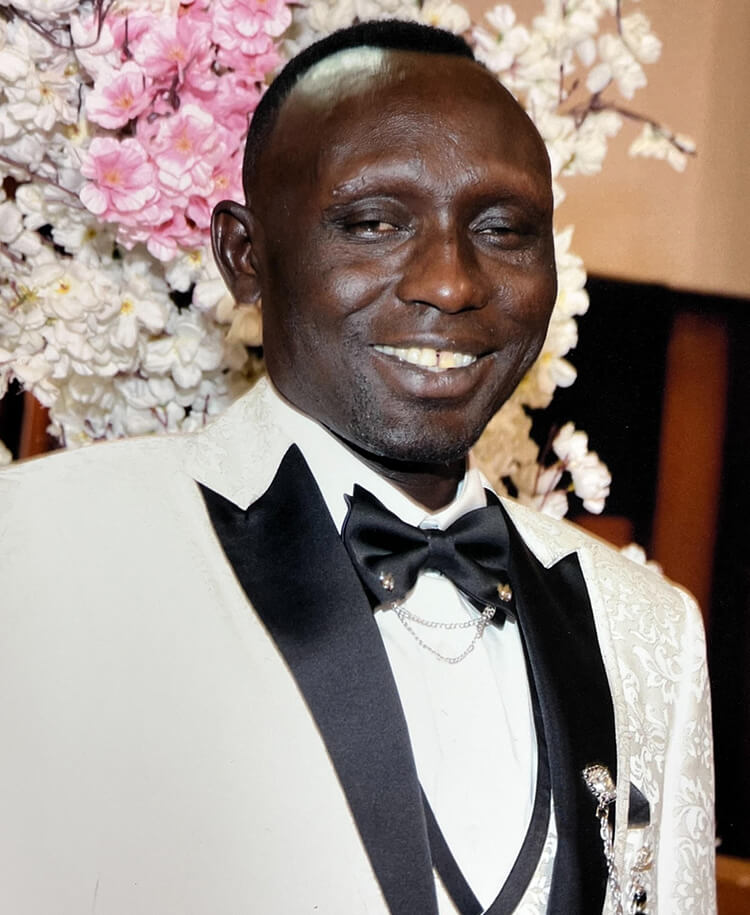 Ibrahim Kodi in a tuxedo in front of flowers