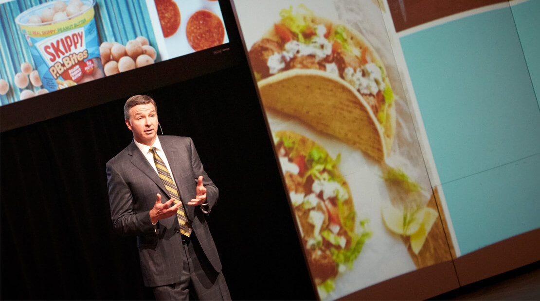 Jim Snee on stage giving a presentation