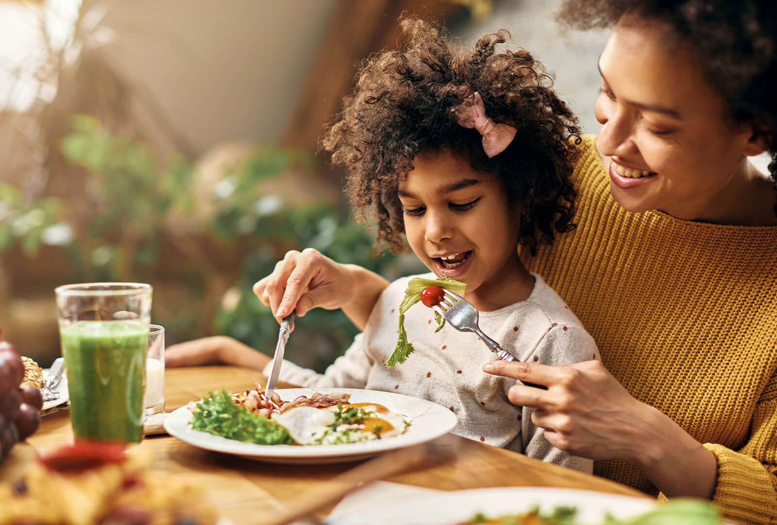 A child sits on her mother's lap trying new food