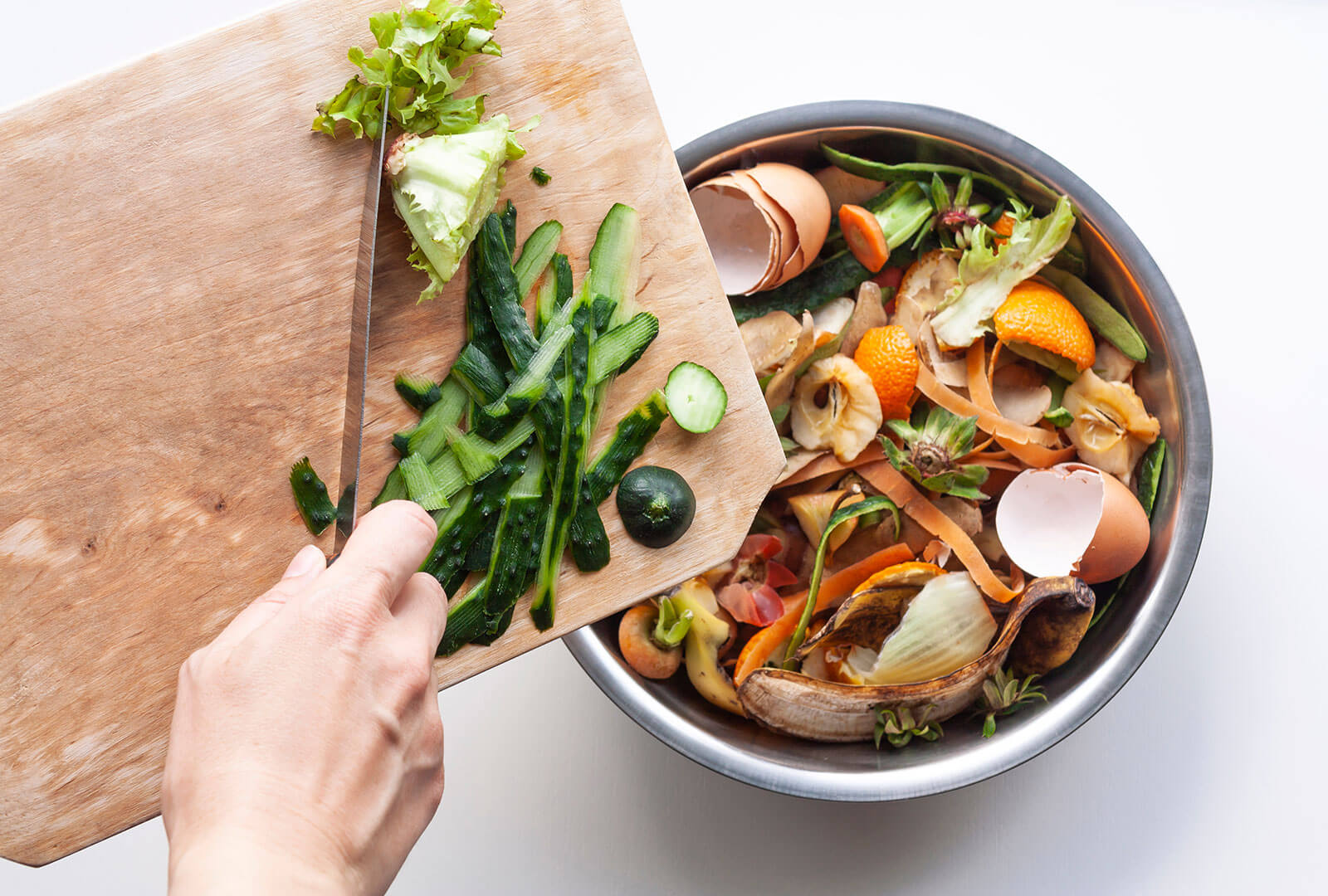 zucchini scraps being added to a bowl full of other vegetables scraps