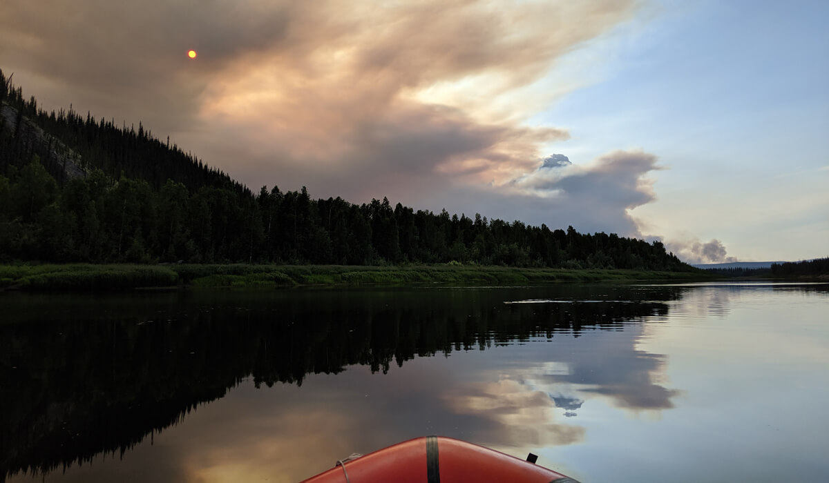 A kayak on a lake looking at a smokey sky